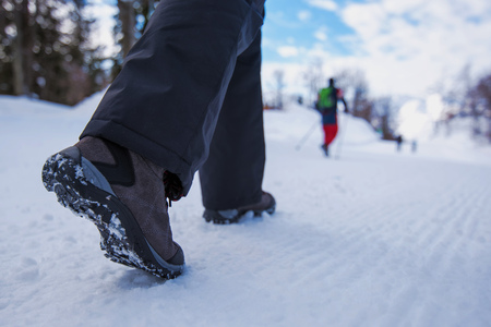 People hiking on snow path in winter time, selective focus on shoesの写真素材