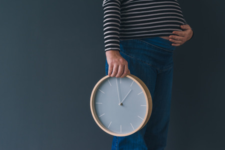 Pregnant female with vintage alarm clock expecting baby in third trimester of pregnancyの写真素材