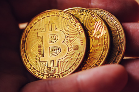Extreme close up of male hand holding Bitcoin, blockchain cryptocurrency coin, selective focusの写真素材