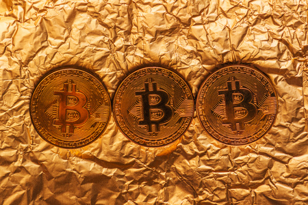 Bitcoin, blockchain cryptocurrency golden coin on gold metal background to emphasize the value of virtual currency in modern worldの写真素材