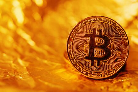 Bitcoin, blockchain cryptocurrency golden coin on gold metal background to emphasize the value of...