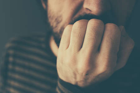 Nervous man bites fingernails,low key close up with selective focus