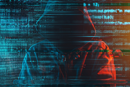 Stereotypical image of computer hacker with hoodie and computer code. Faceless hooded male person...