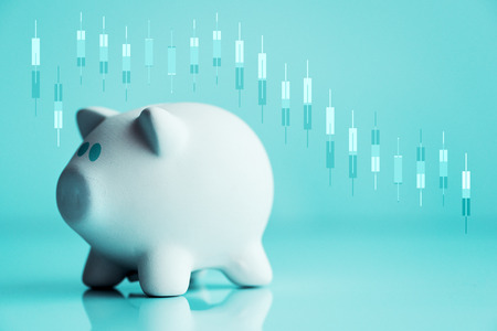 Piggy coin bank and stock candlestick chart going down for investments and savings lossの写真素材
