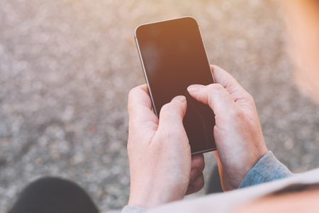 Close up of female hands using smartphone outdoors. Woman in sportswear tapping touch screen of...