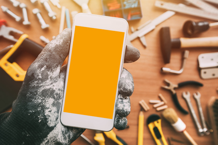 Handyworker smart phone app with blank screen. Repairman holding mobile phone in hand. Copy space...