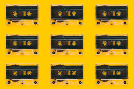 Seamless pattern background of audio cassettes on bright yellow backdrop, minimalistic retro style top view compositionの写真素材