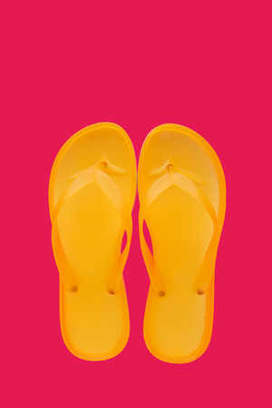 Yellow beach flip flops on neon pink background, top view with copy spaceの写真素材