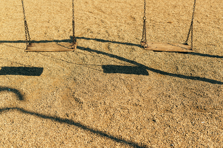 Pair of empty wooden swings with chains on playground