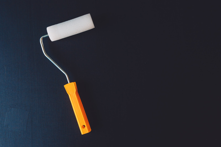 Paint roller on dark surface as copy space, diy tool for home improvement and renovation