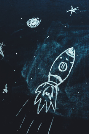 Space rocket with planets and stars doodle drawing on school chalkboard