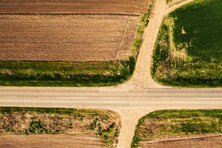 Aerial view of roadway and dirt road intersection, top down from drone pov