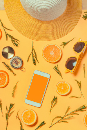 Smartphone mock up with summertime holiday vacation travel accessories on yellow background, flat lay top viewの写真素材
