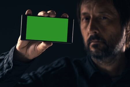 Smartphone mock up in male hand. Adult man holding mobile phone with blank screen as copy space.