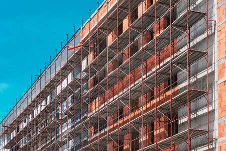 Scaffolding on empty construction site with unfinished incomplete building and blank sky as copy...