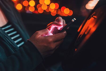 Woman texting on mobile phone in car at night on a parking lot, adult female person using smartphone for communication, selective focusの写真素材