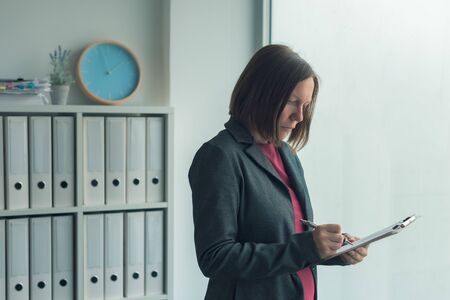 Concerned businesswoman reading business report papers in office, financial data analysis and strategic operations planning conceptの写真素材