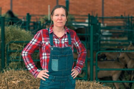 Female farmer posing on goat farm in front of the goatpen