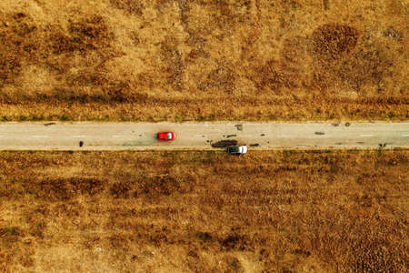 Aerial view of cars on plain countryside landscape road in autumn, drone povの写真素材