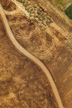 Aerial view of dusty dirt road through grassy plain landscape, top view from drone povの写真素材