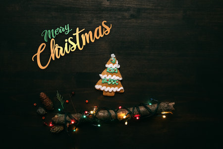 Merry Christmas flat lay top view background with gingerbread tree cookie and twinkle light on wooden boardの写真素材