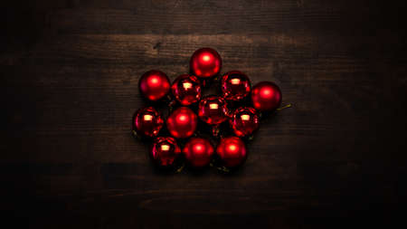 Red Christmas tree balls dancing on wooden table, flat lay top view