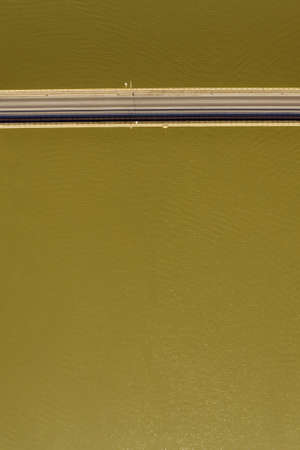 Aerial top view of bridge crossing river with water as copy space, abstract minimalistic composition