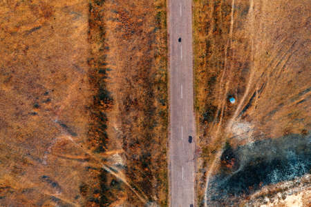 Top view of old worn road through grassy autumn meadow from drone povの写真素材