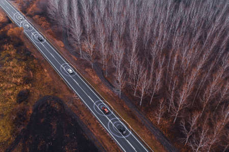Aerial view of autonomous self-driving car on road through countryside from drone pov, conceptual image with digital enhancementの写真素材