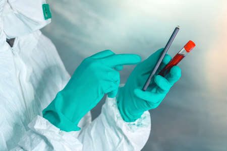 Epidemiologist with smartphone and blood sample in test tube, selective focusの写真素材