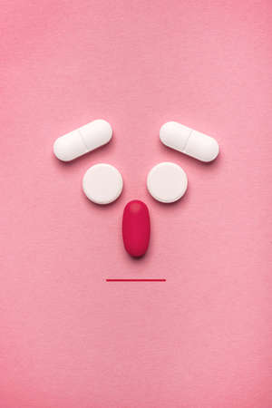Stylized ill face emoticon made of pills and tablets, top view flat lay with copy spaceの写真素材