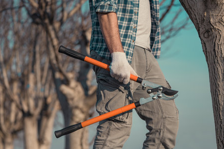 Farmer posing with telescopic ratchet bypass lopper in walnut orchard ready for pruning, selective focusの素材 [FY310177026807]