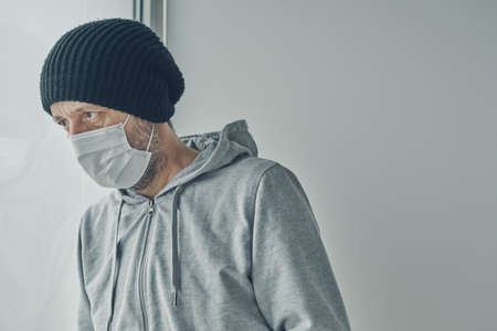 Depressed  patient infected with virus looking out the window of his home quarantine during self-isolationの写真素材