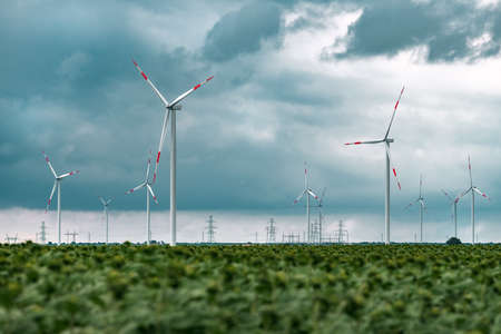 Green energy concept with wind turbines in cultivated agricultural field, renewable energy and...