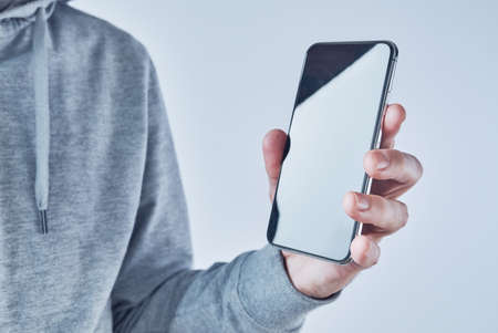Casual adult caucasian male holding modern smartphone in hand, selective focus