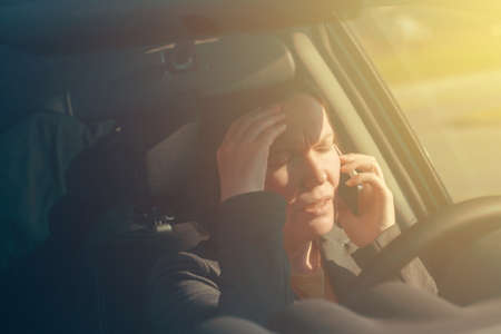 Businesswoman talking on mobile phone in the car while driving to work, selective focusの写真素材