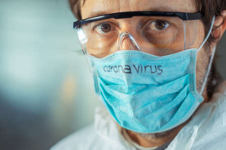Medical worker wearing Coronavirus face protective mask, close up head shot portraitの写真素材