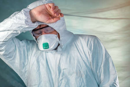 Tired epidemiologist in quarantine, conceptual image of medical specialist wearing protective...