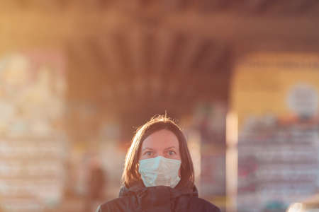 Woman with face protective mask standing on the street, protection from epidemics respiratory virus infectionsの写真素材