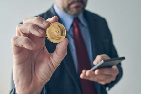 Businessman using smartphone to trade Ethereum cryptocurrency, digital mobile e-wallet conceptual...