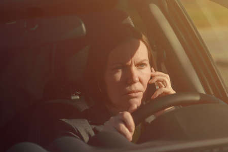 Businesswoman talking on mobile phone in the car while driving to work, selective focus
