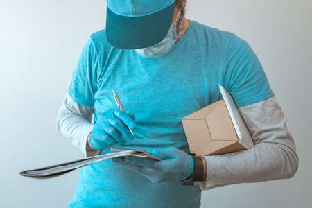 Delivery worker with protective gloves completing package documentation during infectious disease...