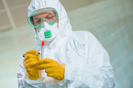 Epidemiologist writing on medical sample dry swab test tube in virus quarantine