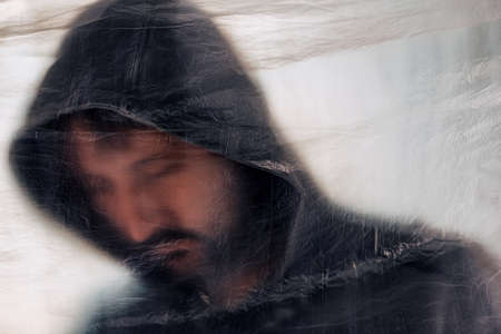 Drug addiction concept, blurred male person with hoodie behind plastic curtain, selective focusの写真素材