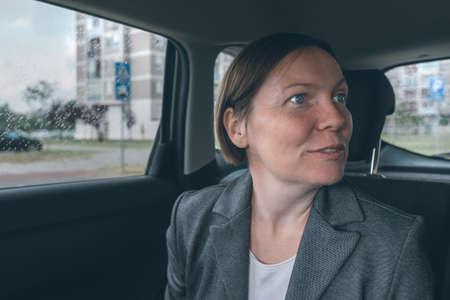 Excited businesswoman at back seat of a car looking out of vehicle windowの写真素材