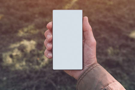Smartphone screen mock up, man holding modern mobile phone device with blank white screen outdoors...