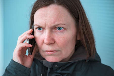 Serious worried woman talking on mobile phone on street, selective focus portraitの写真素材