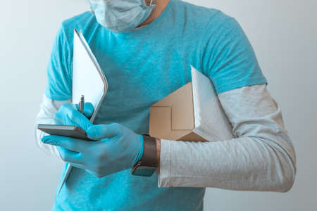 Delivery man with protective clothing using smartphone with protective gloves during viral infection pandemic, selective focusの写真素材
