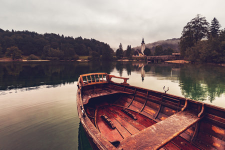 Wooden dinghy rowboat on lake in morning on Lake Bohinj, Sloveniaの写真素材