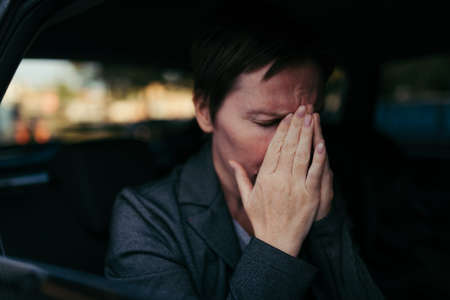 Anxious businesswoman sitting inside of the car, worried and nervous female entrepreneur at vehicle backseatの写真素材